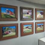 A photo of six oil paintings of covered bridges in Madison County, Iowa.