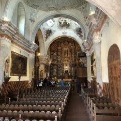 A wider view of the pews and altar of San Xavier.